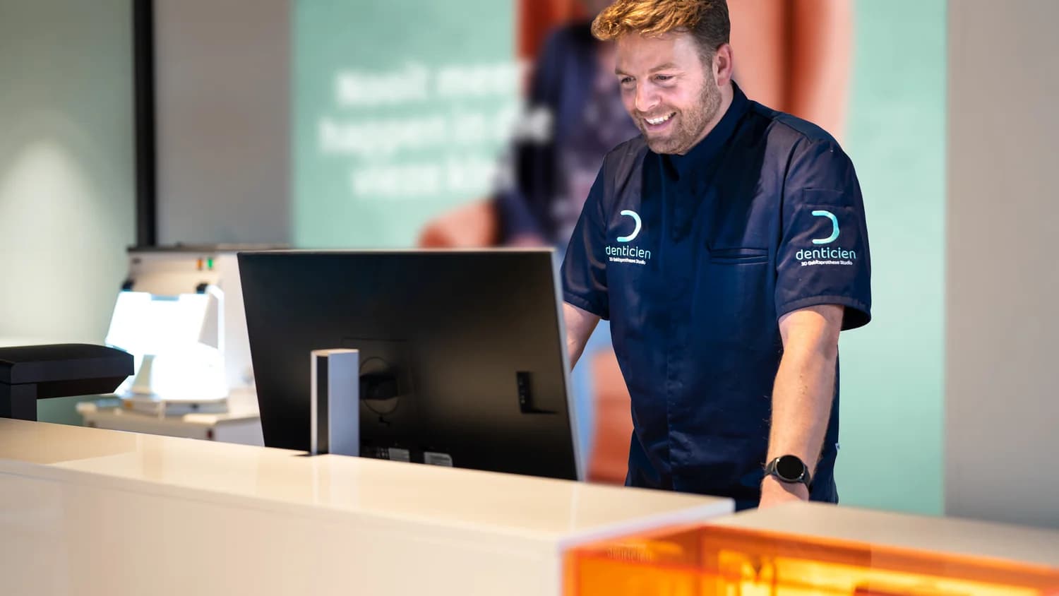 Denticien medewerker aan de balie achter een scherm